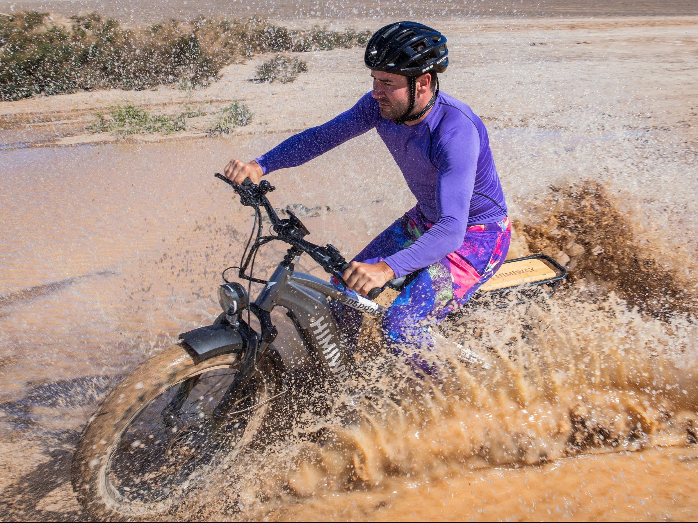 Person riding a bike through water in a desert setting