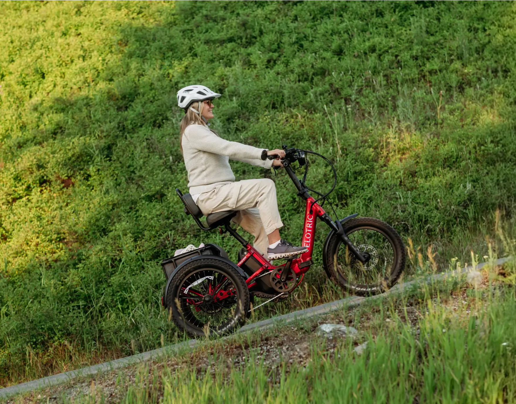Person riding a red electric bike on a grassy hill
