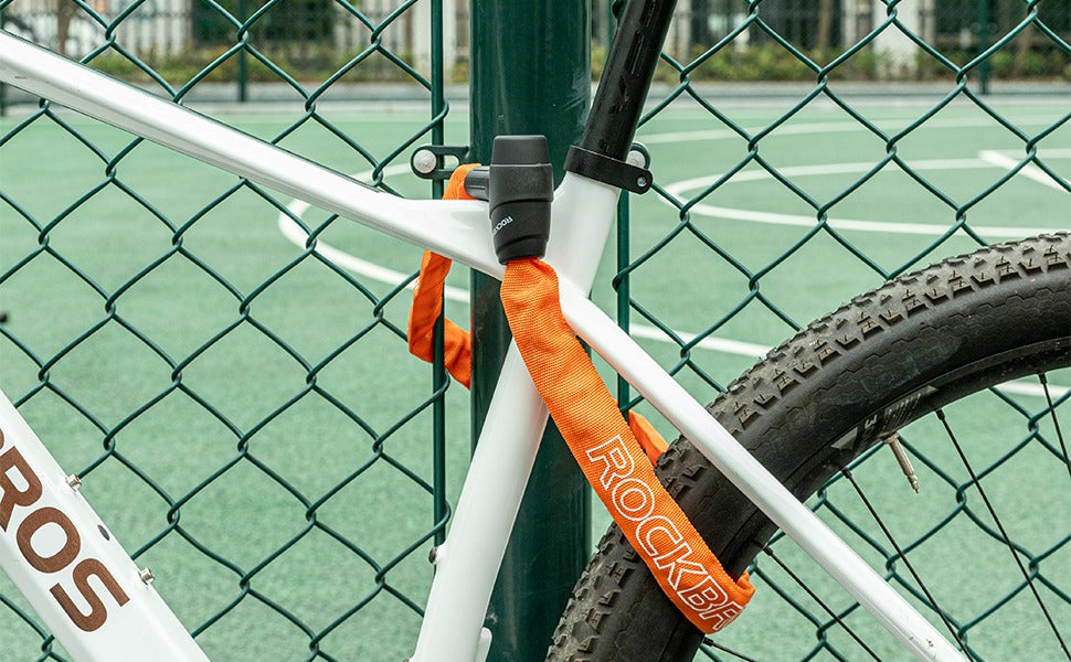 Bicycle locked to a fence with an orange lock on a tennis court