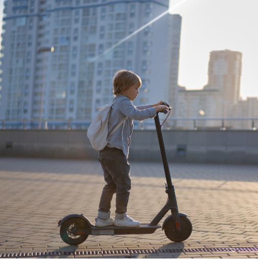 Child riding a scooter on a rooftop with cityscape in the background